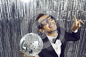 Happy funny young black guy in tuxedo and glasses dancing and having fun at party