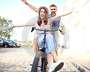 Happy funny young couple riding on bicycle