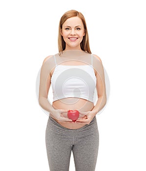 Happy future mother holding small red heart