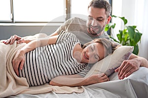 Happy future parents luxuriating in bedding together