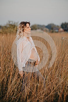 A happy future young mother is a woman in white clothes with a big pregnant belly. Natural landscape. The concept of