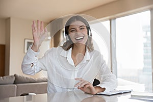 Happy gadget user girl in big earphones waving greeting hand