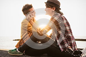 Happy gay couple having tender moments next the sea at sunset