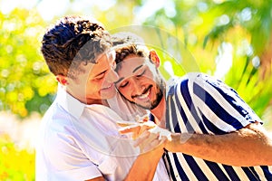 Happy gay couple spending time together in sunny day in green park