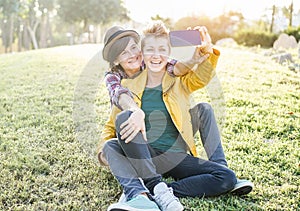 Happy gay couple taking selfie with smartphone in pubblic park at sunset - Homosexuality relationship, lgbt and technology trends