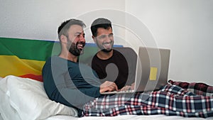 Happy gay men couple using laptop in bed - Homosexual love and gender equality in relationship concept