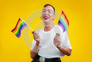 Happy gay with pride movement LGBT holding Rainbow flag isolated yellow background. lgbtq+ photo concept