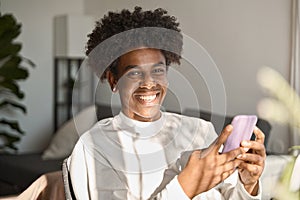 Happy gen z African American teen using mobile phone at home, portrait. photo