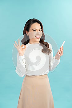 Happy gesturing young cheerful smiling business woman with phone or support operator, showing okay gesture