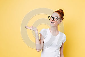 Happy ginger woman in eyeglasses holding invisible copyspace on pound