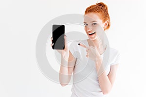 Happy ginger woman showing blank smartphone screen