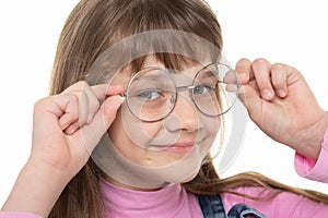 Happy girl adjusts his glasses and looks into the frame, close-up