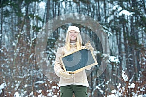 Happy girl with advertising on background of winter forest.