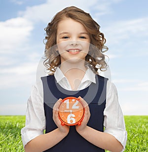 Happy girl with alarm clock over summer background