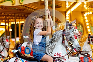 Happy girl in an amusement park rides a horse on a carousel in the summer