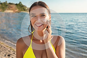 Happy Girl Applying Tanning Lotion On Face Sunbathing On Beach