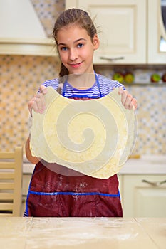 Happy girl in apron keeps dough for pizza cooking photo