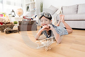 Happy girl as pilot playing with wooden airplane