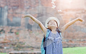 Happy girl with backpack play flower