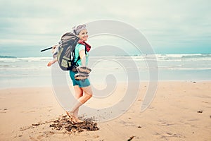Happy girl backpacker traveler runs barefoot on the sand ocean b