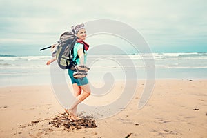 Happy girl backpacker traveler runs barefoot on the sand ocean b photo