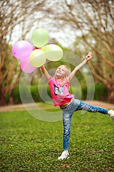 Happy girl with balloons jumping in city park celebrating summer lifestyle freshness of nature