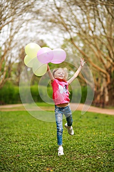 Happy girl with balloons jumping in city park celebrating summer lifestyle freshness of nature