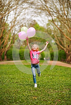 Happy girl with balloons jumping in city park celebrating summer lifestyle freshness of nature