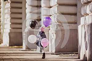 Happy girl with balloons run on the city street, Budapest, Hungary.