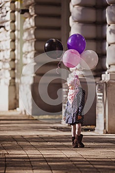 Happy girl with balloons run on the city street, Budapest, Hungary.