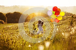 Happy girl with balloons running across the field