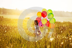 Happy girl with balloons walking across the field