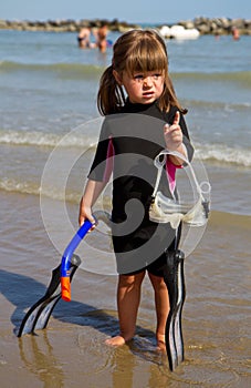 Happy girl on beach with colorful face masks and snorkels, sea i photo