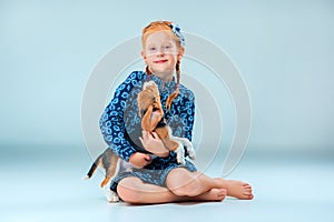 The happy girl and a beagle puppie on gray background