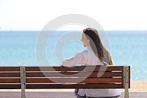 Happy girl on a bench contemplating ocean on the beach
