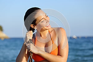 Happy girl in bikini draining hair after bath on the beach