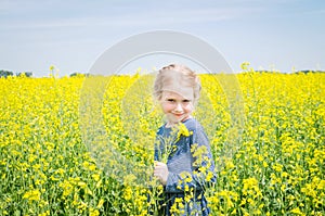 Happy girl on blooming rapeseed field in summer