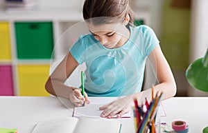 Happy girl with book writing to notebook at home