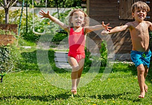 Happy girl and boy caught mid-run flying water droplets around