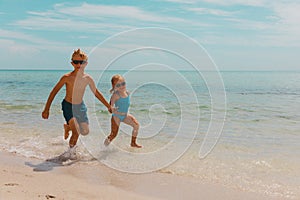 Kids- girl and boy run play with waves on beach