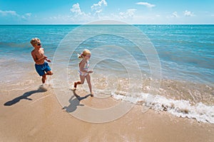 Happy girl and boy run and play with water at beach