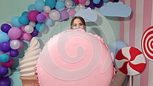 Happy girl in bright clothes holding in his hand a huge marshmallow. Candy girl.