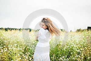 Happy girl on the camomile field, summer sunset. in a white dress. running and spinning, the wind in my hair, life style