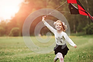 Happy girl in casual clothes running with kite in the field. Beautiful nature