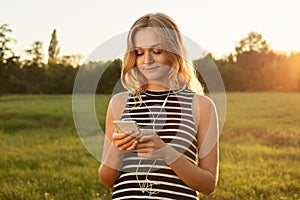 A happy girl with charming smile looking in her mobile phone and typing something.