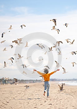 Happy girl chasing birds on the beach