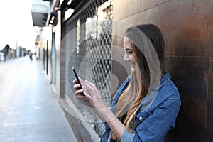 Happy girl checks smart phone in the street