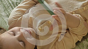 Happy girl child with blond hair and pigtails, lying on the sofa, using the phone, smiling, portrait