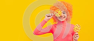 Happy girl child with orange hair in pink poloneck have fun holding lollipops, girlhood. Funny teenager child on party photo