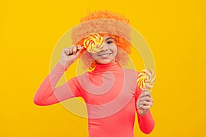 Happy girl child with orange hair in pink poloneck have fun holding lollipops, girlhood photo